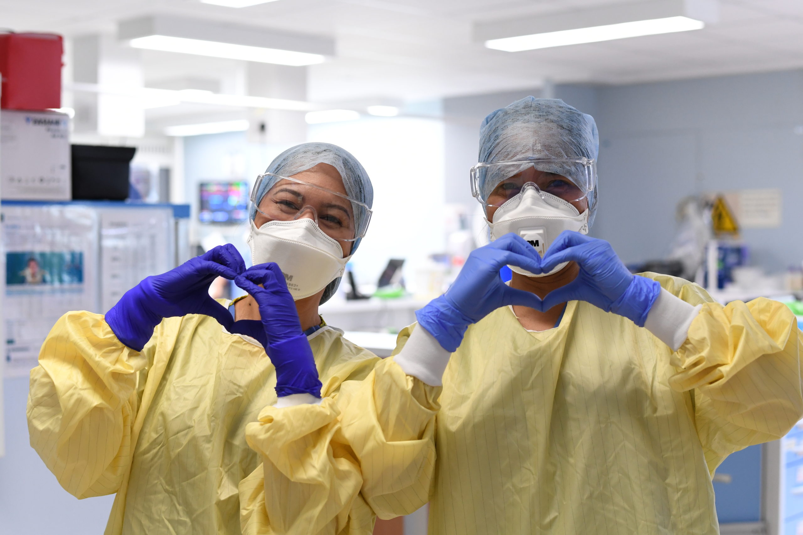Two nurses in scrubs making aheart shape with their hands
